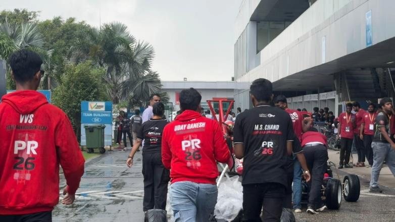Team members in PR26 jackets pushing the car towards technical inspection